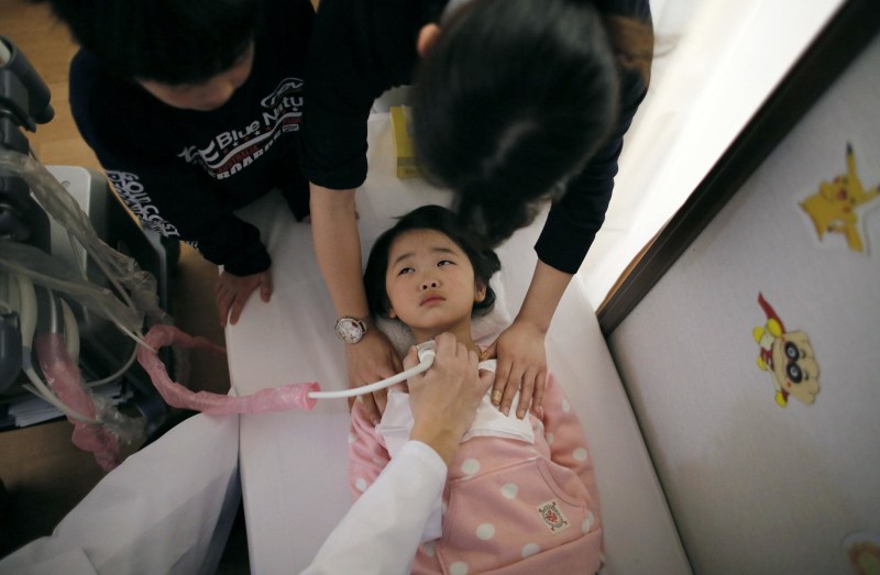 Image: A doctor conducts a thyroid examination on five-year-old girl 