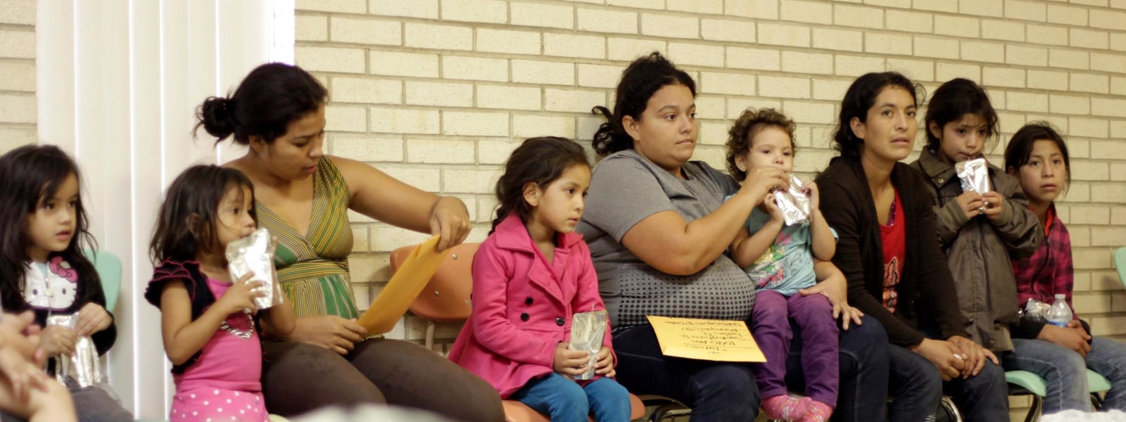Image: Migrants sit at the Sacred Heart Catholic Church temporary migrant shelter in McAllen, Texas