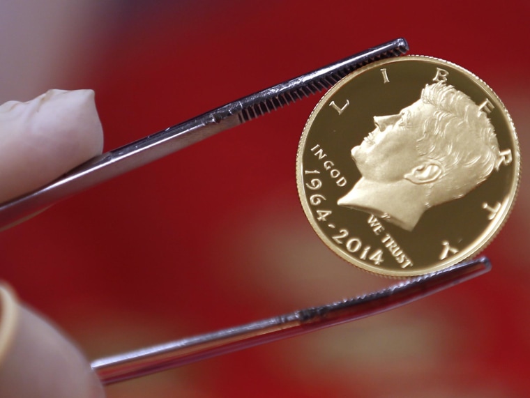 Obraz: świeżo stemplowana złota moneta prezydenta Johna F. Kennedy 'ego jest badana w Mennicy USA w West Point