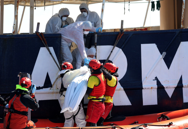 Image: Lifeguards lift the body of a migrant during a search and rescue operation off the Libyan coast