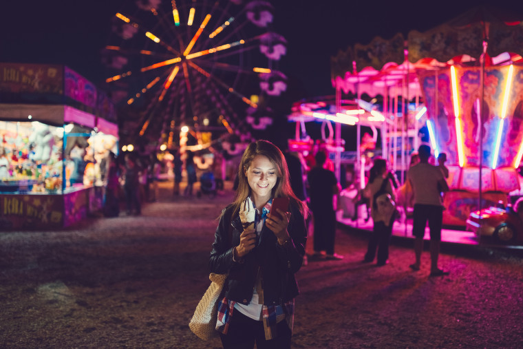 Image: Smiling woman texting at the amusement park