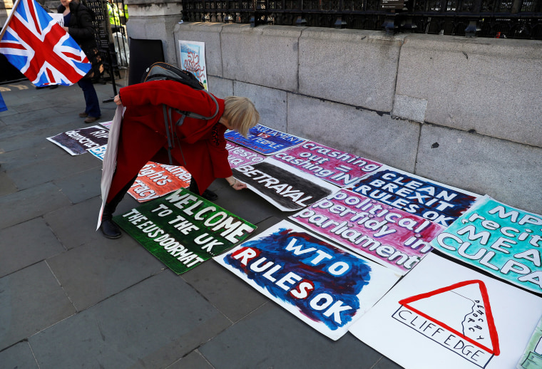 Image: A person arranges the Brexit signs at the entrance to the Parliament in London