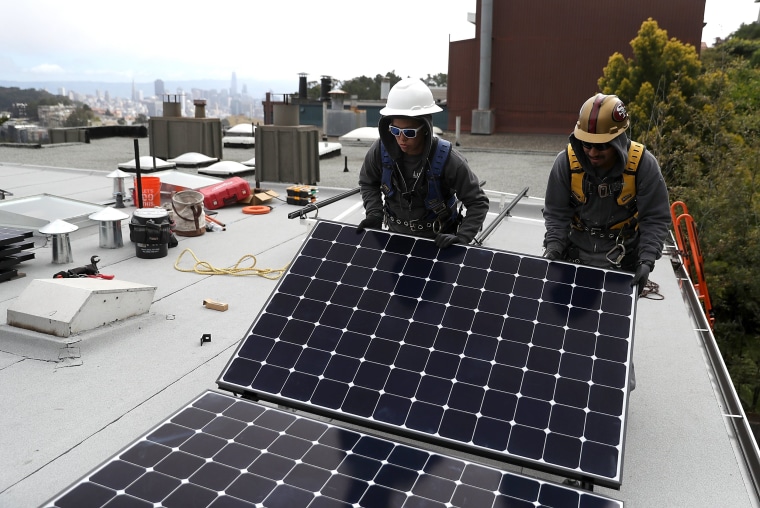 Image: Workers install solar panels on a roof