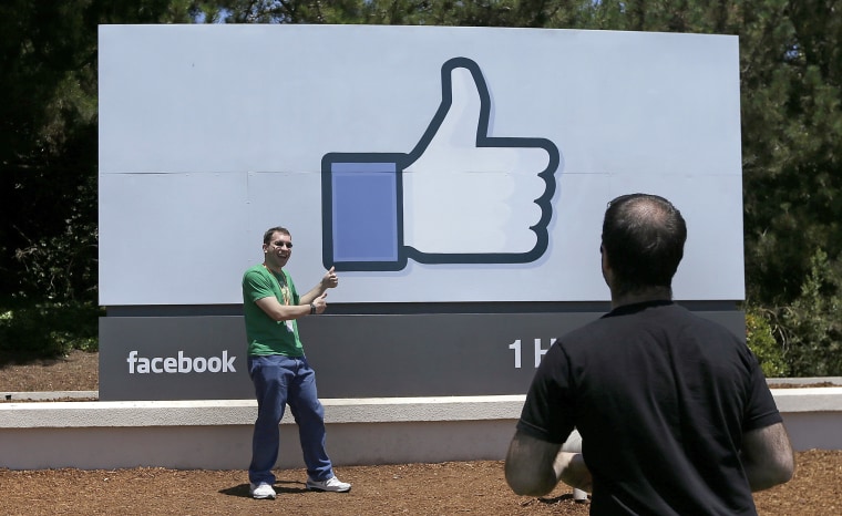 A man poses for photos in front of the Facebook sign on the company's campus in Menlo Park, California, in 2014.