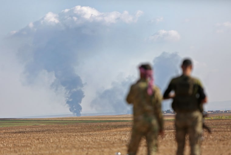 Image: Turkey-backed Syrian fighters watch as smoke billows in the distance during clashes between Syrian regime forces, and Turkish forces, 15kms east of the northeastern town of Ras al-Ein