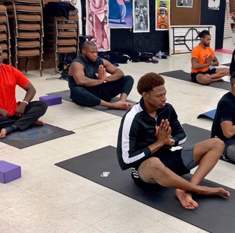 Men in a seated pose in Sherri Doucette's "Broga - Yoga for the Brothers" class at the Pan African Connection in South Dallas.
