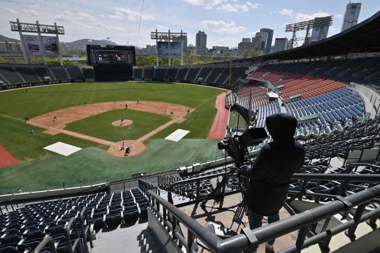 Image: A cameraman records footage among empty stands during a pre-season baseball game between Seoul-based Doosan Bears and LG Twins at Jamsil stadium in Seoul