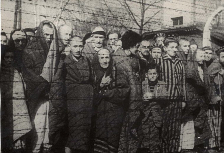 Image: Holocaust survivors stand behind a barbed wire fence after the liberation of Nazi German death camp Auschwitz-Birkenau in 1945 in Nazi-occupied Poland.