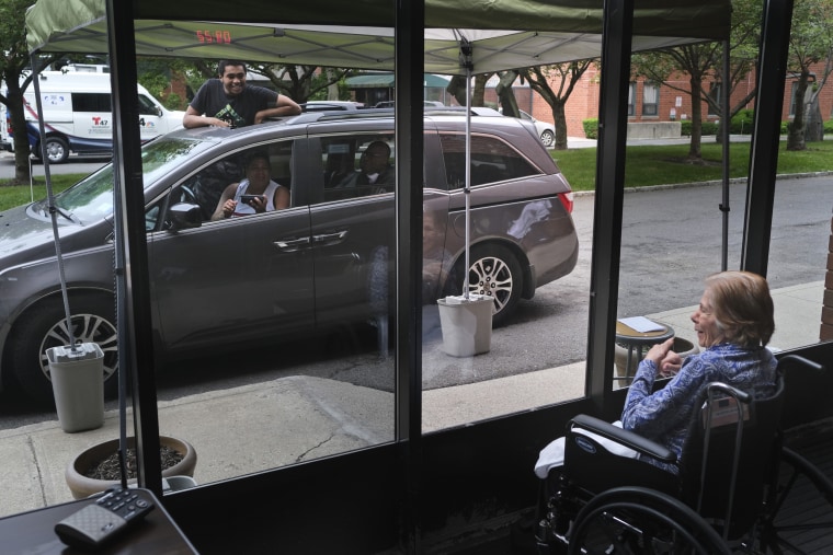Gloria DeSoto, 92, visits with her family in their car through a window of the Hebrew Home at Riverdale in Bronx, N.Y., on June 11.