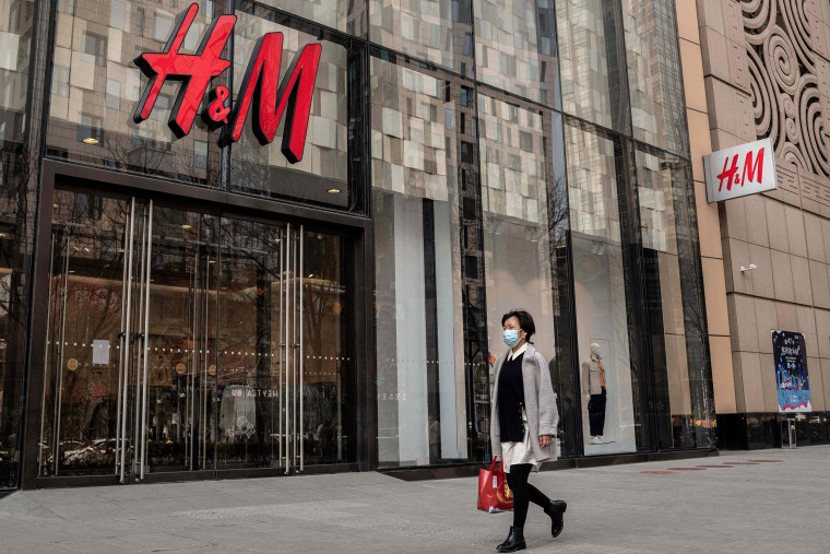 Image: A woman walks past a store of Swedish clothing giant H&M in Beijing