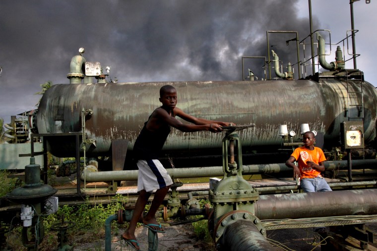 Image: Children play on an abandoned oil flow station near smoke from a burning oil pipe in Kegbara-Dere, Nigeria, in 2007.
